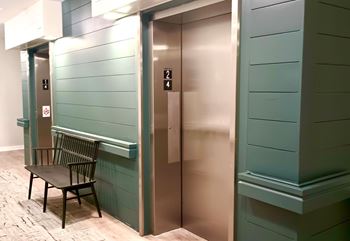 A bench is next to an elevator with the number 2 on it.